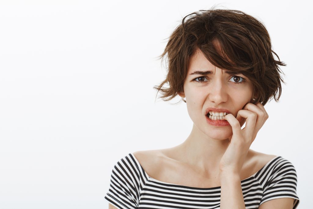 close up worried guilty cute woman grimacing nervously